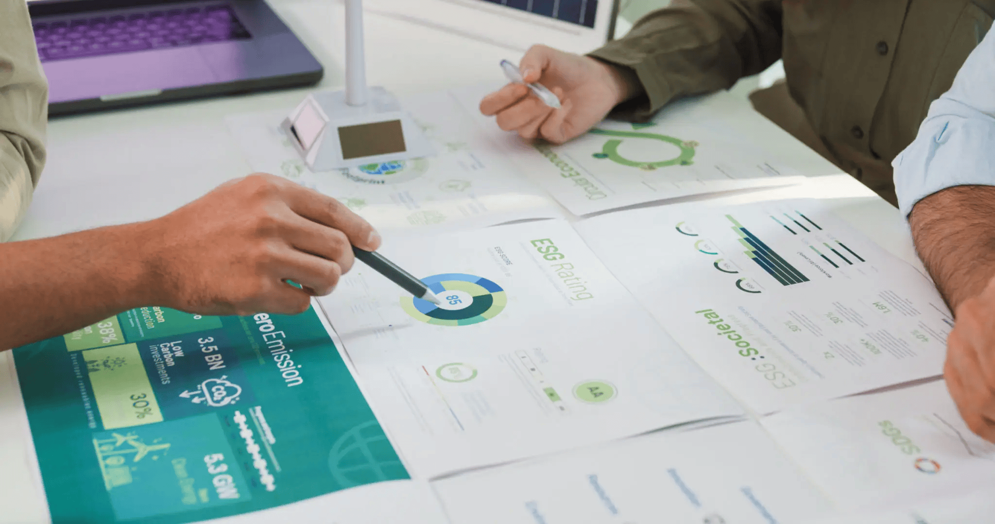Hands pointing at sustainability report charts