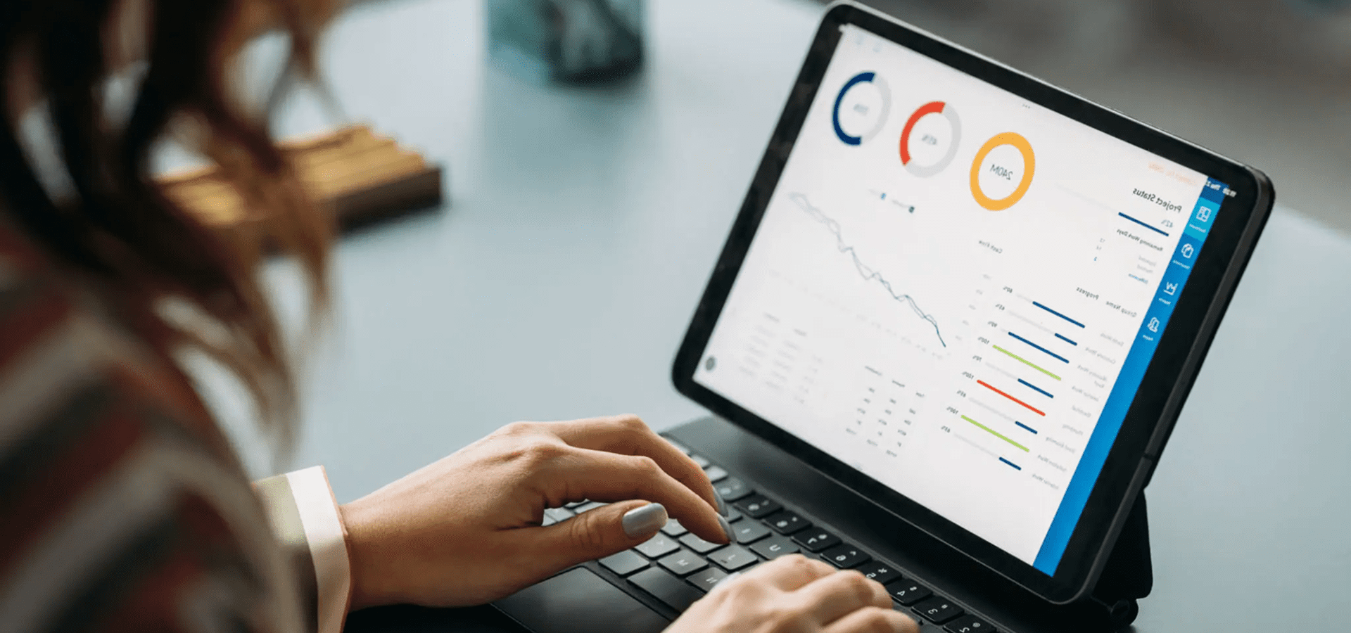 Hands typing on tablet displaying data charts