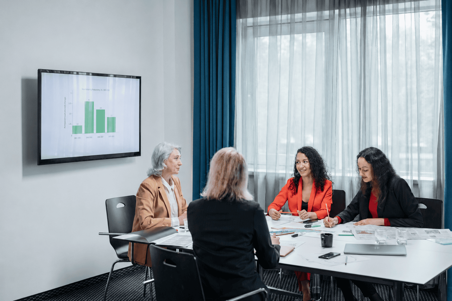 Business meeting with four women discussing data.