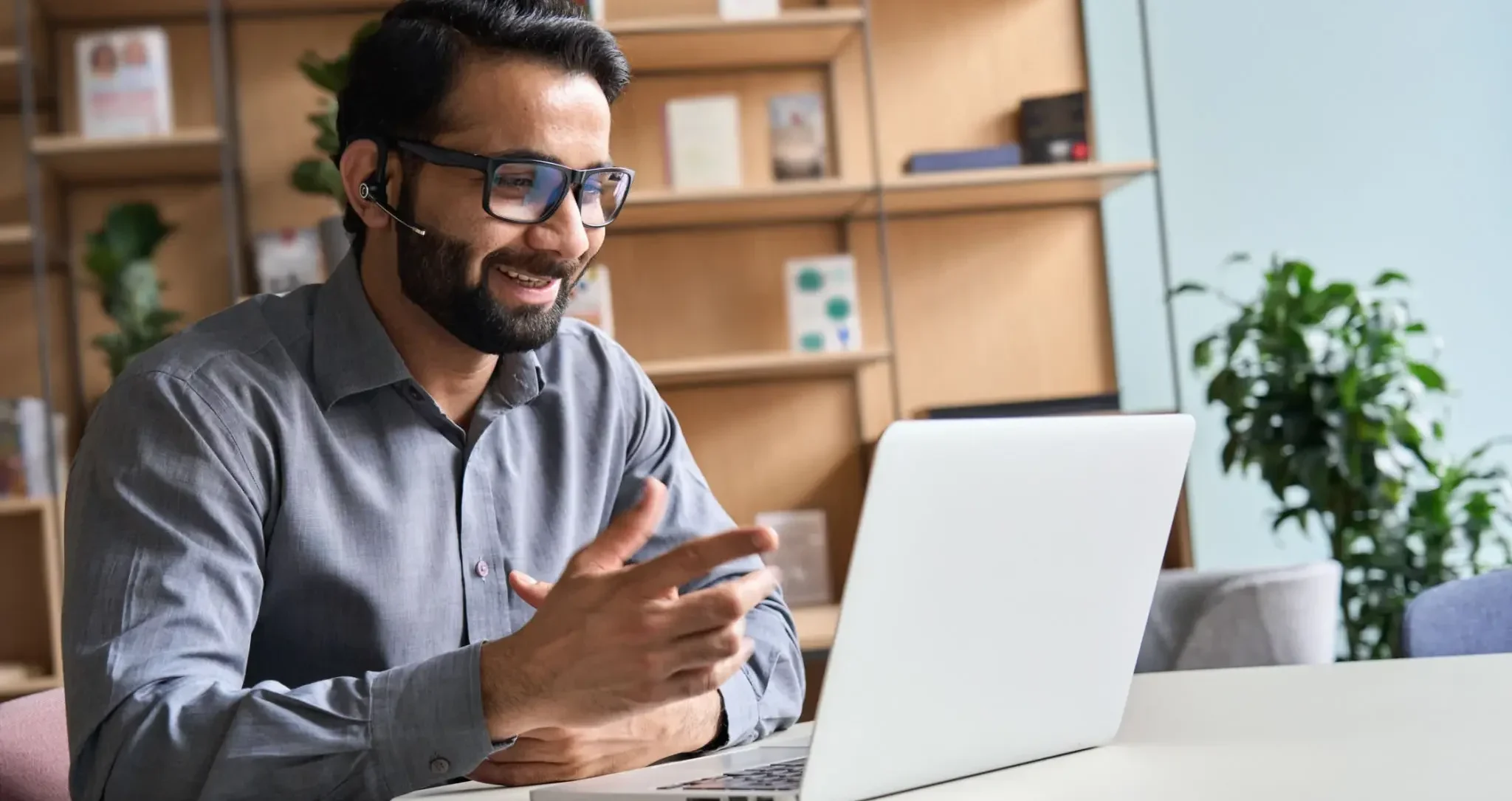 Smiling man with headset video calling on laptop