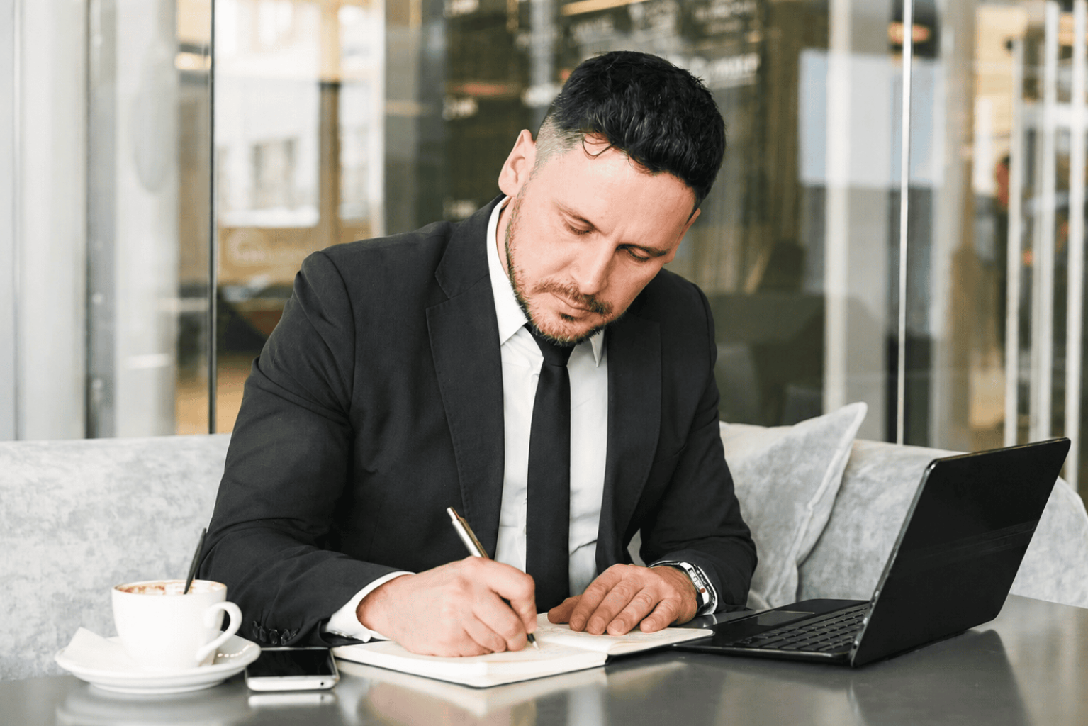 Businessman writing notes in a modern café.